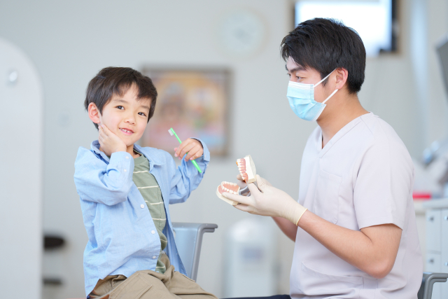 歯医者と一緒に歯磨きしている男の子